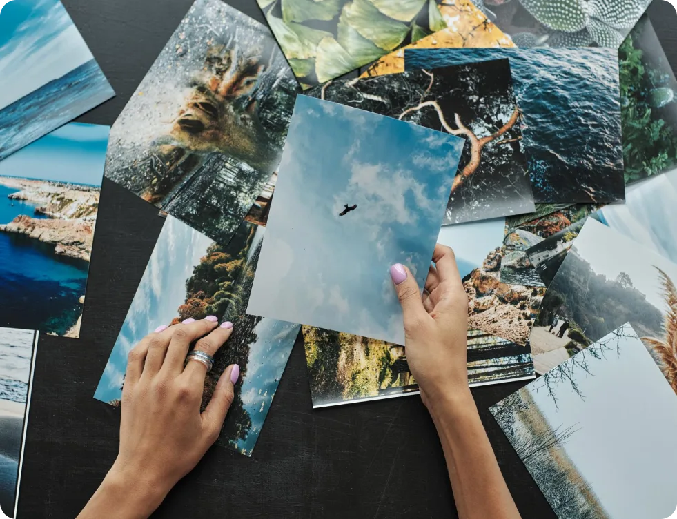 Personne tenant des photos imprimées au-dessus d'un collage désordonné, symbolisant les défis liés au recadrage et à la sélection des photos.